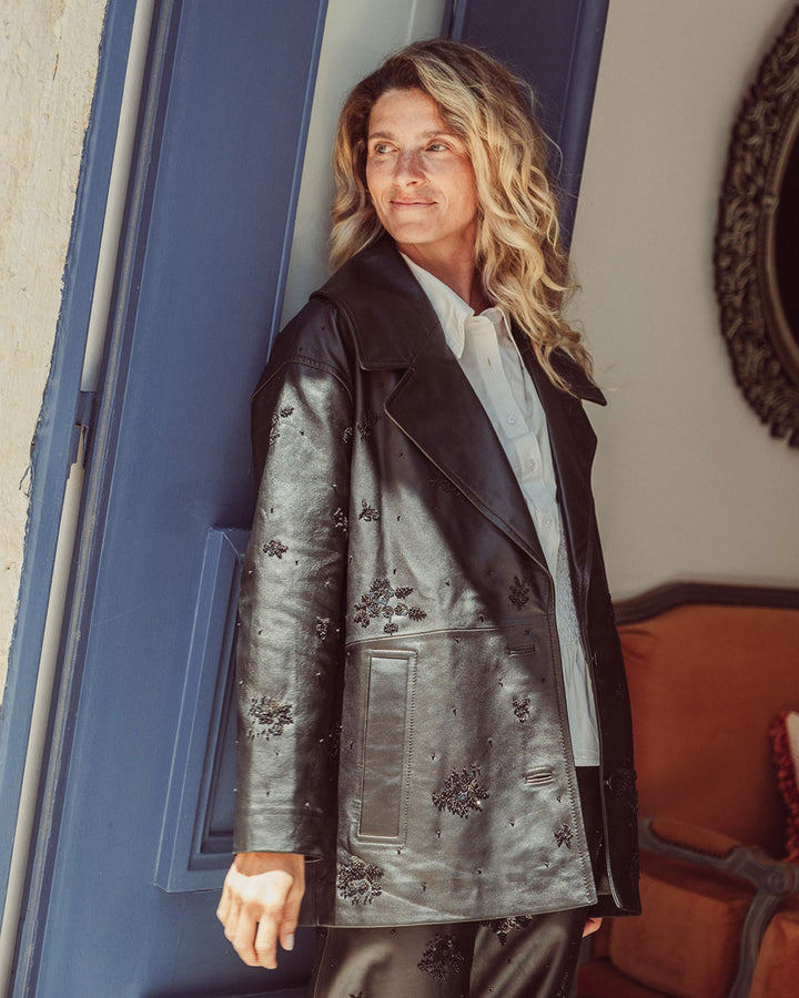 Chaqueta aviadora de cuero natural negro para mujer con solapas anchas y bordados florales hechos a mano de la colección Her Story moda sostenible urco.