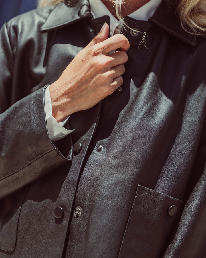 Chaqueta de cuero natural negro para mujer de corte recto con vuelo peplum recogido y broches metálicos de la colección Her Story moda sostenible urco.