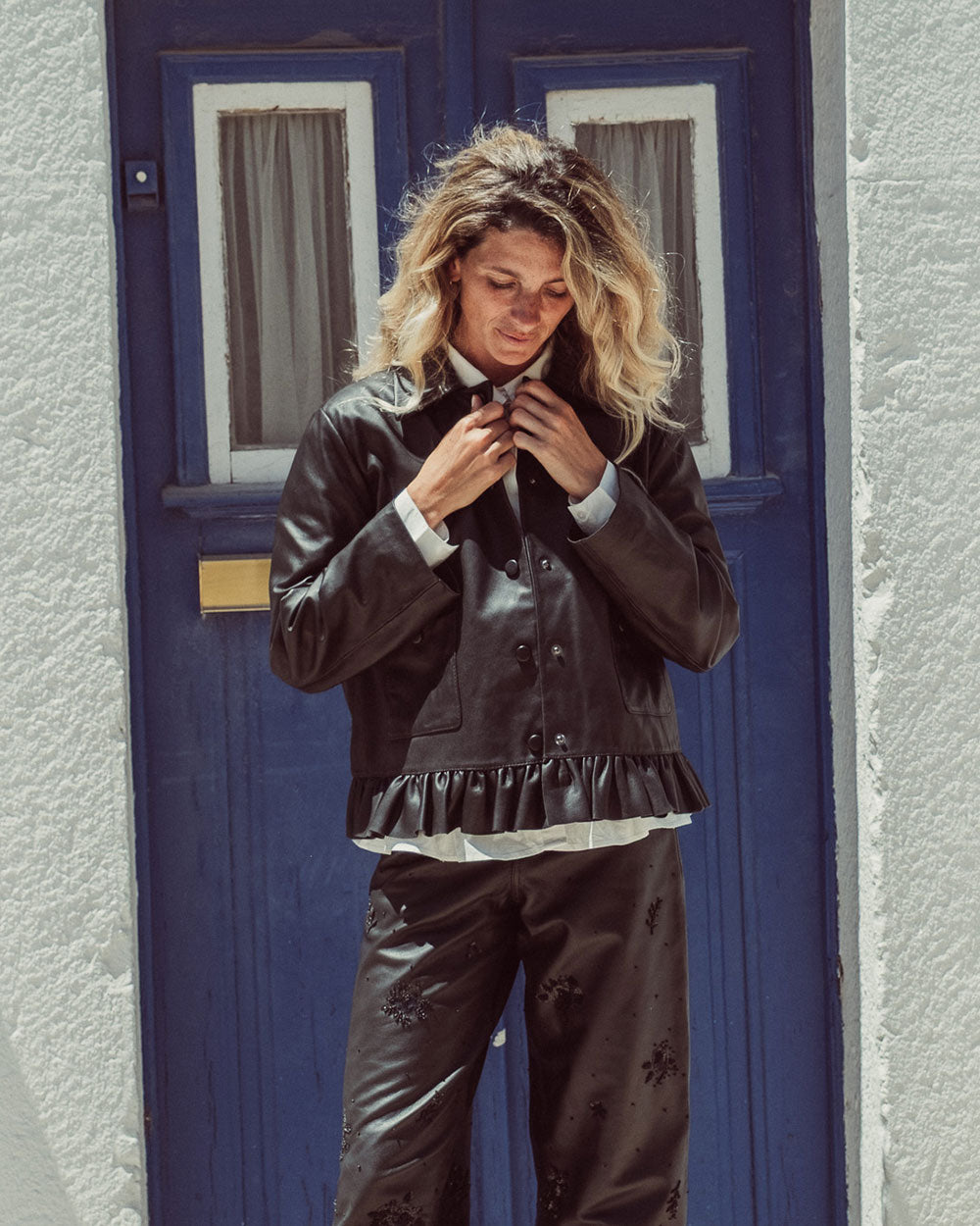 Chaqueta de cuero natural negro para mujer de corte recto con vuelo peplum recogido y broches metálicos de la colección Her Story moda sostenible urco.