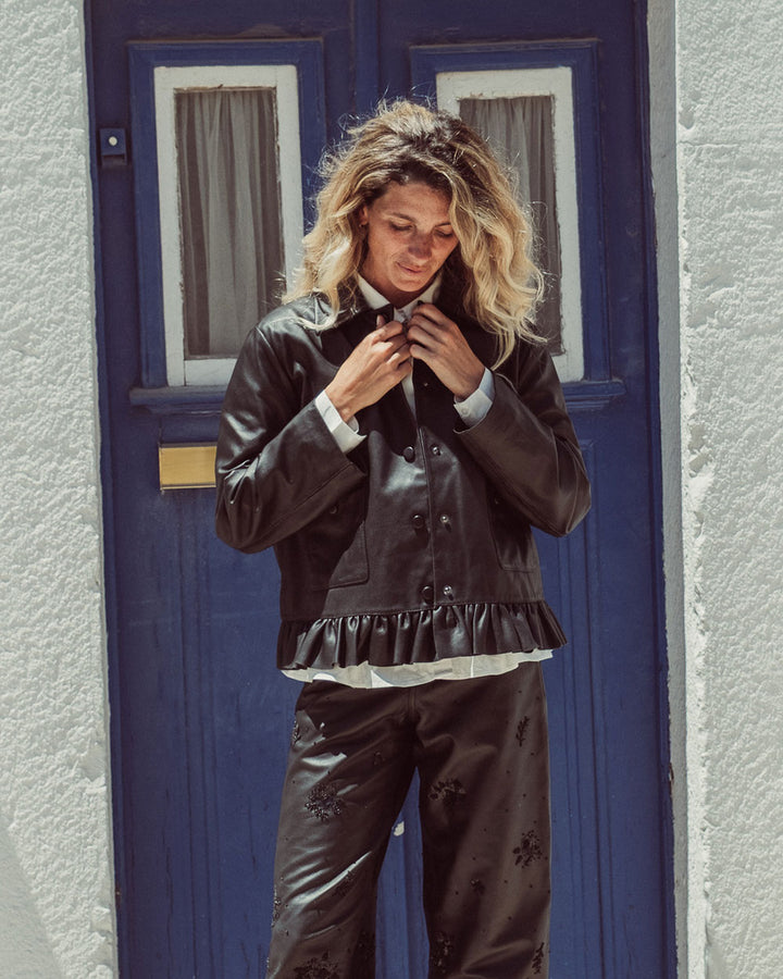 Chaqueta de cuero natural negro para mujer de corte recto con vuelo peplum recogido y broches metálicos de la colección Her Story moda sostenible urco.
