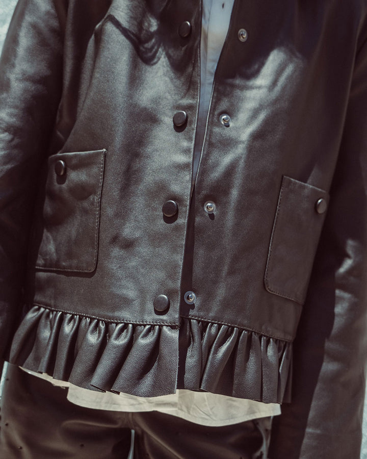 Chaqueta de cuero natural negro para mujer de corte recto con vuelo peplum recogido y broches metálicos de la colección Her Story moda sostenible urco.
