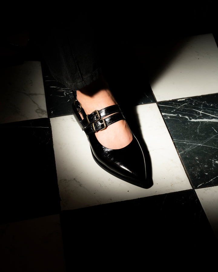 Zapato Luciana de cuero charol negro con punta estilizada, tres tiras con hebillas metálicas y taco de 2 cm, calzado artesanal hecho en Italia.